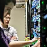 woman and man technicians working on computer server farm